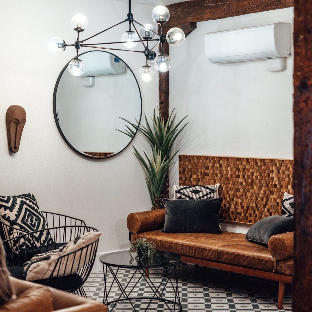 Modern interior with a mirror, some sofas, and fake plants. An example of your typical rent vacation flat, with cheap items but very fashionable
